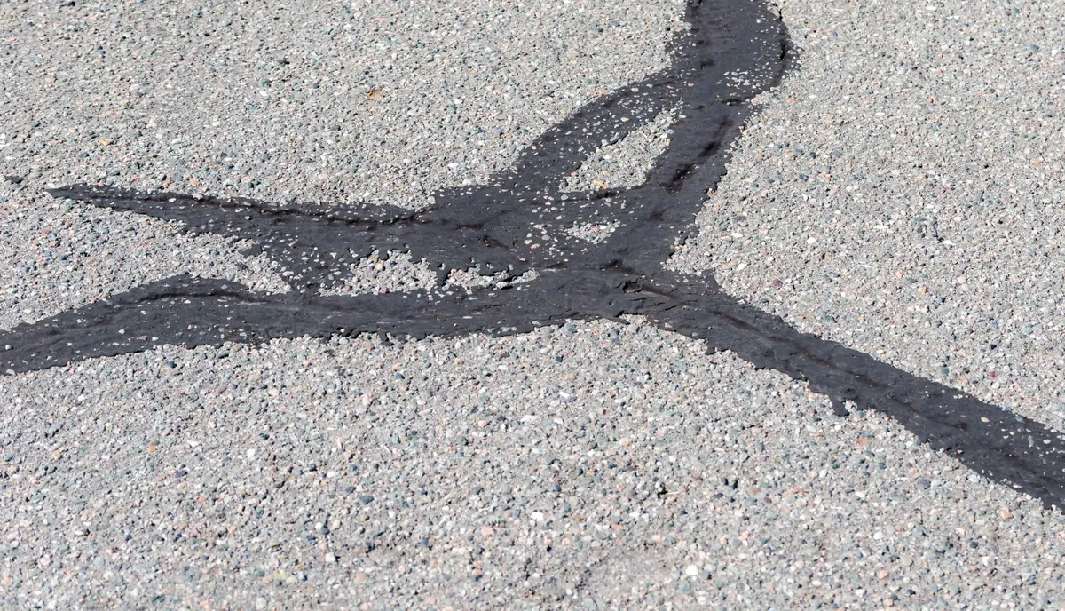 Close-up of asphalt cracks filled with black crack sealant