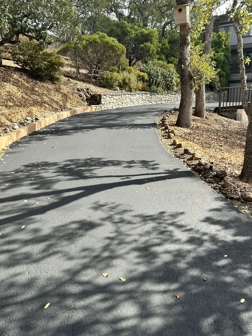 Asphalt driveway bordered by a stone retaining wall